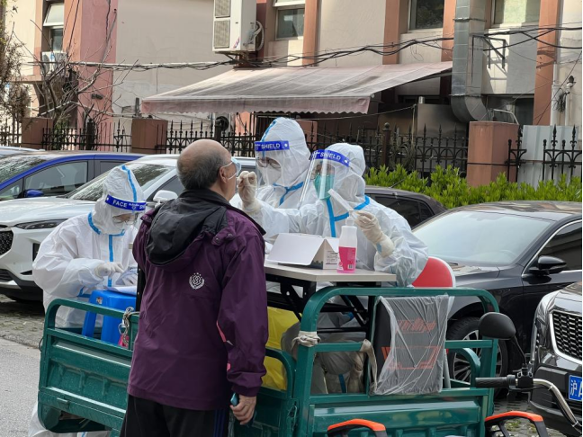 社区志愿者用三轮车把江西援沪医疗队的队员们载到每个单元口进行核酸采集。